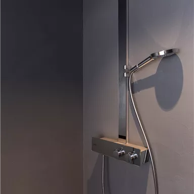 A modern shower with shiny fixtures on a dark wall. The showerhead is designed in an elegant, minimalist shape.
