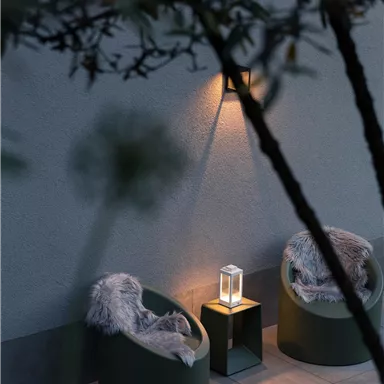 Cozy outdoor seating area with two round chairs and a lamp. A calm atmosphere with subdued lighting.