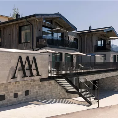A modern building with a wood and stone facade. The large terrace offers a view of the surroundings.
