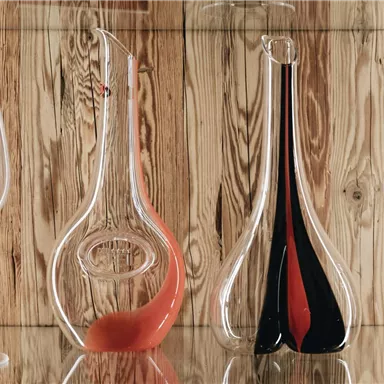 An elegant display cabinet with decorative carafes and wine glasses. The carafes are designed in various shapes and colors.