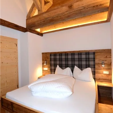 A modern bedroom with wood-paneled walls and a cozy bed design. The atmosphere is warm and inviting.