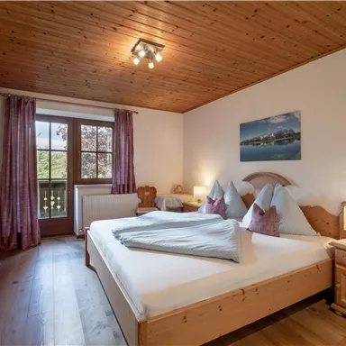 Ein gemütliches Schlafzimmer mit Holzvertäfelung und einem großen Fenster. Es gibt ein Doppelbett mit bequemen Kissen und eine angenehme Beleuchtung.