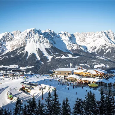 A picturesque mountain landscape with snow-covered peaks. In the foreground, there are skiers and a cozy mountain cabin.
