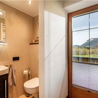 A modern bathroom with bright walls and an elegant sink. A beautiful mountain landscape can be seen through the window.