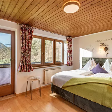 A cozy bedroom with a double bed and comfortable pillows. Large windows offer a beautiful view of nature.