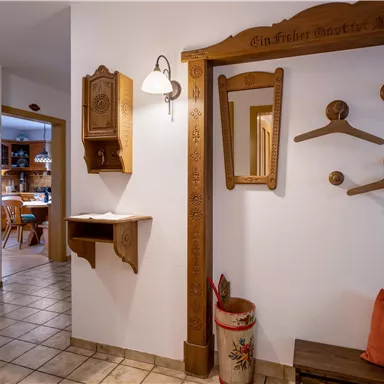 Ein einladender Flur mit rustikalen Holzverzierungen und einer gemütlichen Atmosphäre. Auf der linken Seite befindet sich eine praktische Garderobe mit Kleiderhaken.