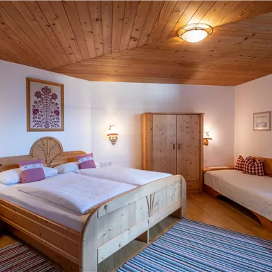 Ein gemütliches Schlafzimmer mit Holzdekor und zwei Betten. Die Wände sind hell gestrichen und dekoriert mit Bildern.