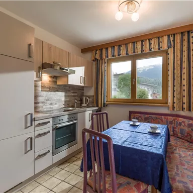 Eine gemütliche Küche mit einem Essbereich und Blick auf die Berge. Die Einrichtung ist modern und funktional.