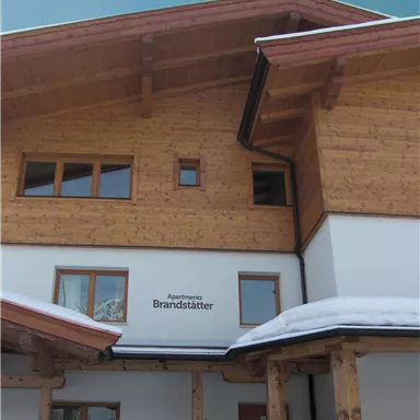 A modern wooden house with an inviting façade. The snow on the ground creates a cozy atmosphere.