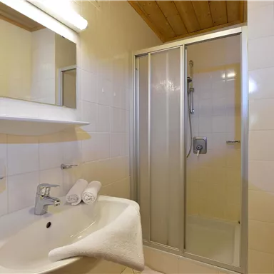 A modern bathroom with a shower and a sink. Bright tiles and wooden details create an inviting atmosphere.