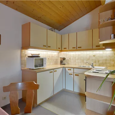 A bright kitchen with wooden details and modern appliances. It is well-organized and offers ample space for meal preparation.