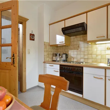 A modern kitchen with wood details and white cabinet design. Fresh apples are on the table.