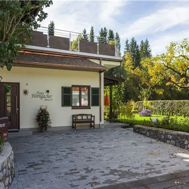 A charming house with a well-kept garden and green trees. The entrance area is inviting and friendly designed.