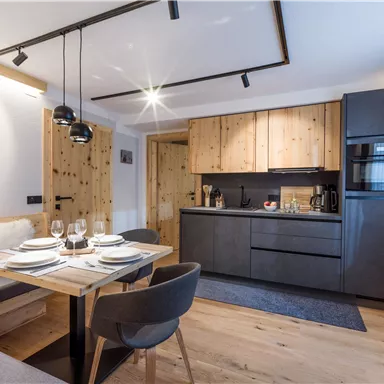 A modern kitchen with wooden details and elegant furniture. The dining area is tastefully set and invites you to eat.