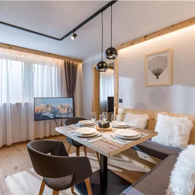A modern dining room with a wooden table, elegant chairs, and beautiful decoration. Large windows let in plenty of light and create an inviting atmosphere.