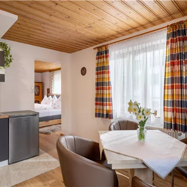 Eine gemütliche Ferienwohnung mit einer kleinen Küchenzeile und einem Essbereich. Große Fenster sorgen für helles Licht und eine angenehme Atmosphäre.