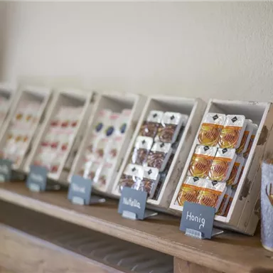 A selection of packaged sweets and honey in attractive boxes. Next to the products is a decorative candle holder.