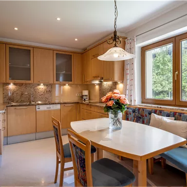 A modern kitchen with wooden cabinets and a bright table. Window view of a green garden.
