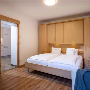 A cozy bedroom with a double bed and wooden cabinets. The room is bright and furnished in a modern style.