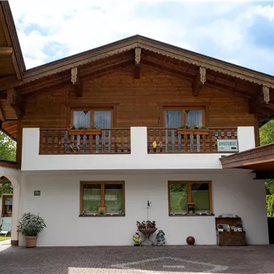 Ein traditionelles alpenländisches Haus mit Holzverkleidung und einem Balkon. Der Eingangsbereich ist gemütlich und lädt zum Verweilen ein.