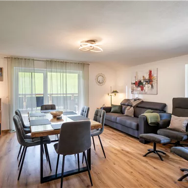 A modern living room with a large dining table and comfortable seating.
Large windows let in plenty of light and offer a view of the outdoors.