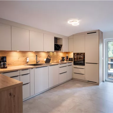Modern kitchen with bright cabinets and wooden details. Large windows provide plenty of light and a view outside.