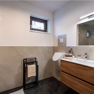 A modern bathroom with a glass shower and a wooden sink. The walls are painted in neutral tones, and there is a large mirror above the sink.