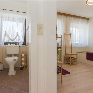 A modern bathroom with a toilet and bright colors. The area is well-lit and has a friendly atmosphere.