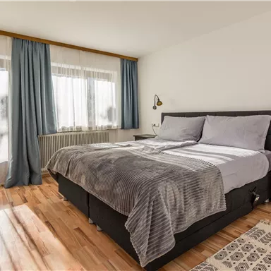 A modern bedroom with a large bed and cozy bedding.
Large windows provide plenty of daylight and a bright atmosphere.