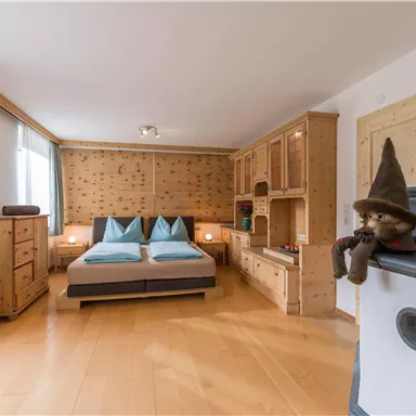 A cozy bedroom with two beds and wooden furniture. The walls are light, and there is a familiar, rustic charm.