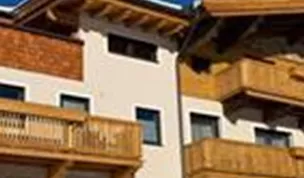 A modern house with wooden balustrades and a typical Alpine style. The clear blue sky complements the inviting facade.
