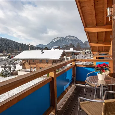 A beautiful balcony with a view of a snowy landscape with mountains in the background. The atmosphere is cozy and inviting.