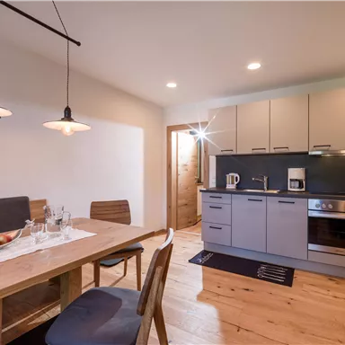 A modern kitchen with a wooden dining area. The rooms are bright and invitingly designed.
