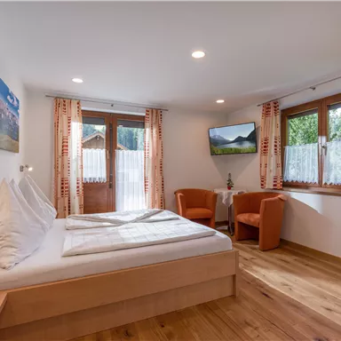 A cozy bedroom with a double bed and modern furniture. Large windows offer a view of nature and provide plenty of daylight.