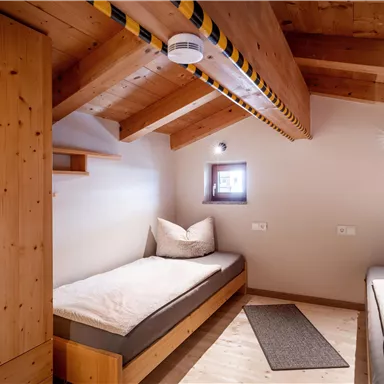 Ein gemütliches Zimmer mit Holzverkleidung und zwei Einzelbetten. Es gibt Raum für persönlichen Gegenstände und sanfte Beleuchtung.