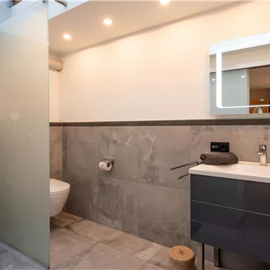 Ein modernes Badezimmer mit einer Dusche aus Glas und stilvollen Fliesen. Der Raum ist hell und ansprechend gestaltet.