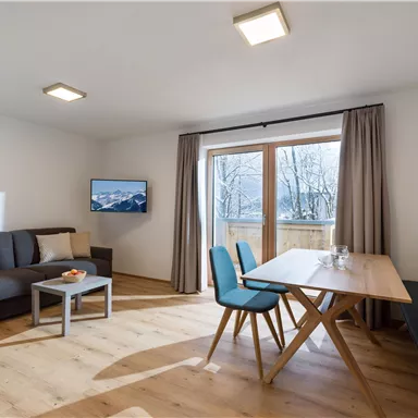 Eine moderne Wohnung mit einem gemütlichen Wohnzimmer und einer Essbereich. Große Fenster bieten einen Blick nach draußen und lassen viel Licht herein.