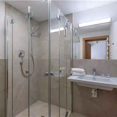 Ein modernes Badezimmer mit Glasdusche und hellem, neutralem Farbton. Der Raum ist sauber und gut beleuchtet.