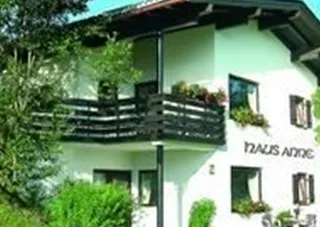 Ein modernes Haus mit einem Balkon und schönen Blumen. Es steht in einer grünen Umgebung mit Bäumen und Gras.