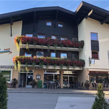 Ein charmantes Gebäude mit bunten Blumenbalkonen. Im Erdgeschoss befinden sich ein Café und eine Konditorei.