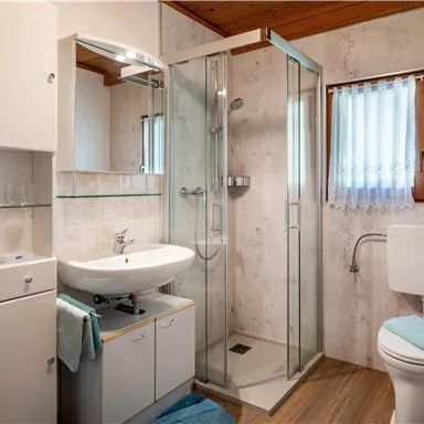 A modern bathroom with a shower and a sink. Bright walls and a wooden ceiling create an inviting atmosphere.