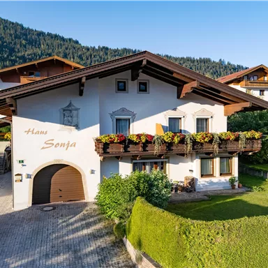 A charming house with a lovely balcony and flower boxes.
Surrounded by green meadows and mountains in the background.
