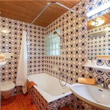 A colorful bathroom with a colorful tile pattern. It includes a bathtub, a sink, and a shower.