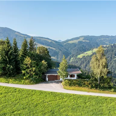 A picturesque house amidst green hills and dense forests. The surroundings are idyllic and offer an impressive mountain landscape.