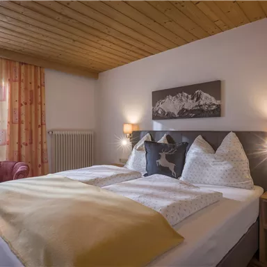 A cozy bedroom with a double bed and warm colors. Large windows provide plenty of daylight and an inviting atmosphere.