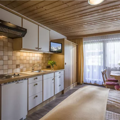 A cozy kitchen with wooden ceilings and modern appliances. The room is bright and friendly with plenty of natural light.