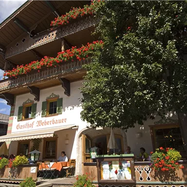A charming inn with blooming flowers on the balcony. The facade is designed in a traditional style and invites you to linger.