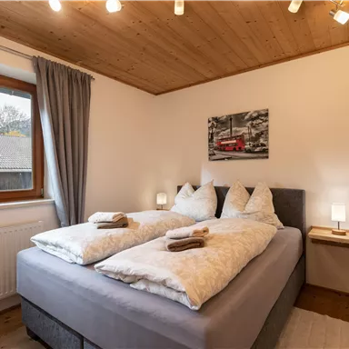 A cozy bedroom with a double bed and modern nightstands. Natural light streams through the window, creating an inviting atmosphere.