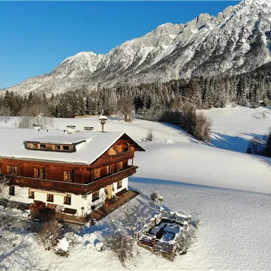 Ein charmantes Holzhaus im Schnee mit Blick auf majestätische Berge. Die Umgebung ist winterlich und, mit weißem Schnee bedeckt.