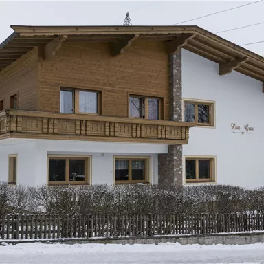 A beautiful, modern house made of wood and stone. Surrounded by snow and mountains, it conveys a cozy atmosphere.